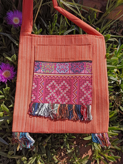 Thai Woven Cotton Sling Bag Terracotta Pink Floral Border – front view showing pink cross-stitch geometric panel with zip and multicolour fringe
