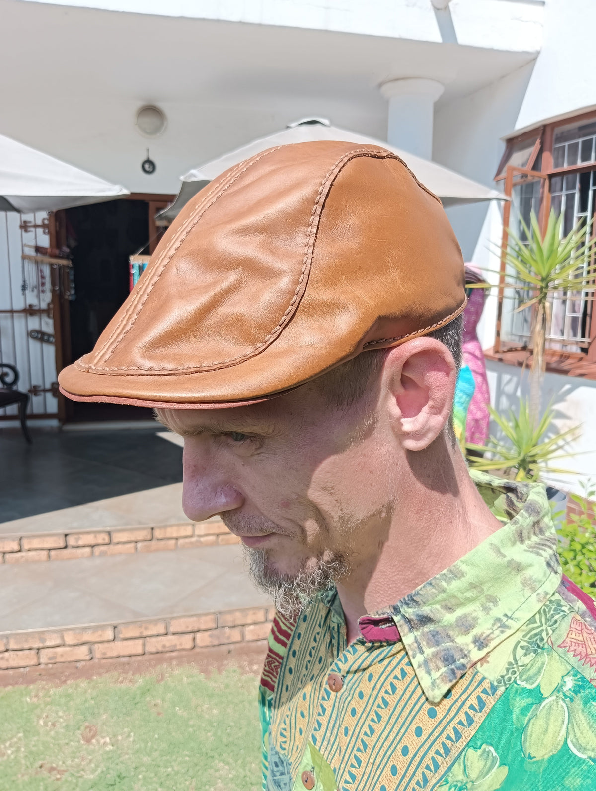 Leather Andy Flat Cap in Tan – side profile view on male model showing stitched panel seams and cognac leather tone